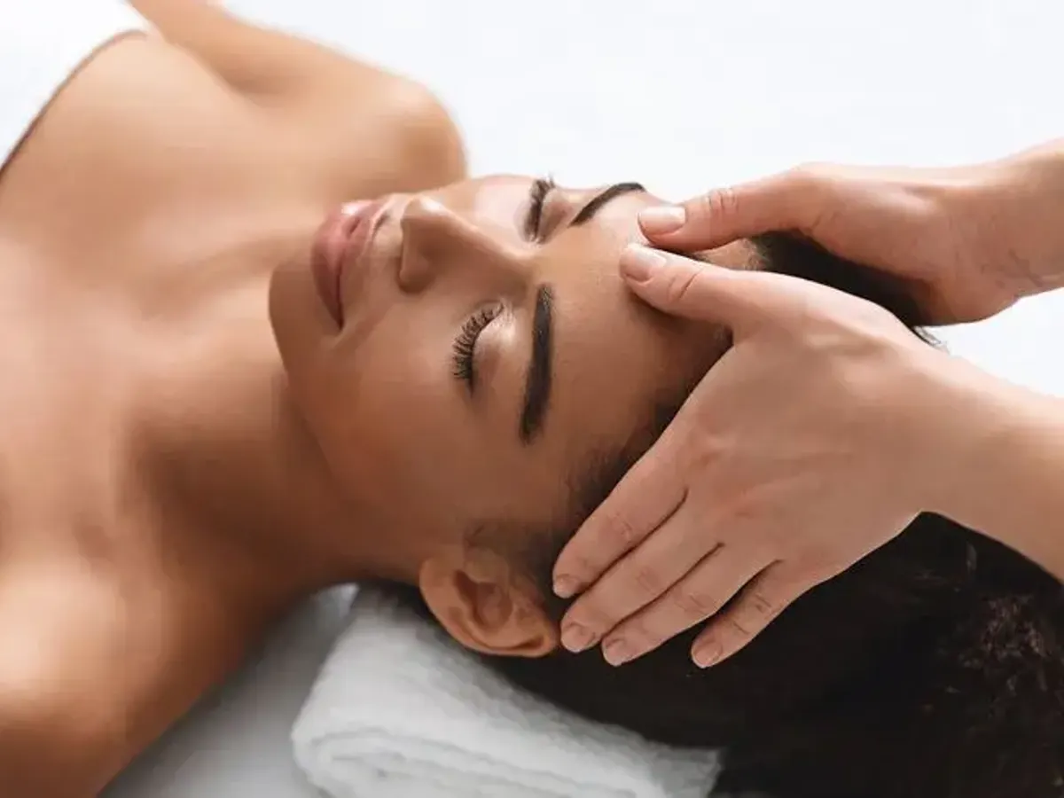 Massage du visage réalisé à la main sur une cliente allongée