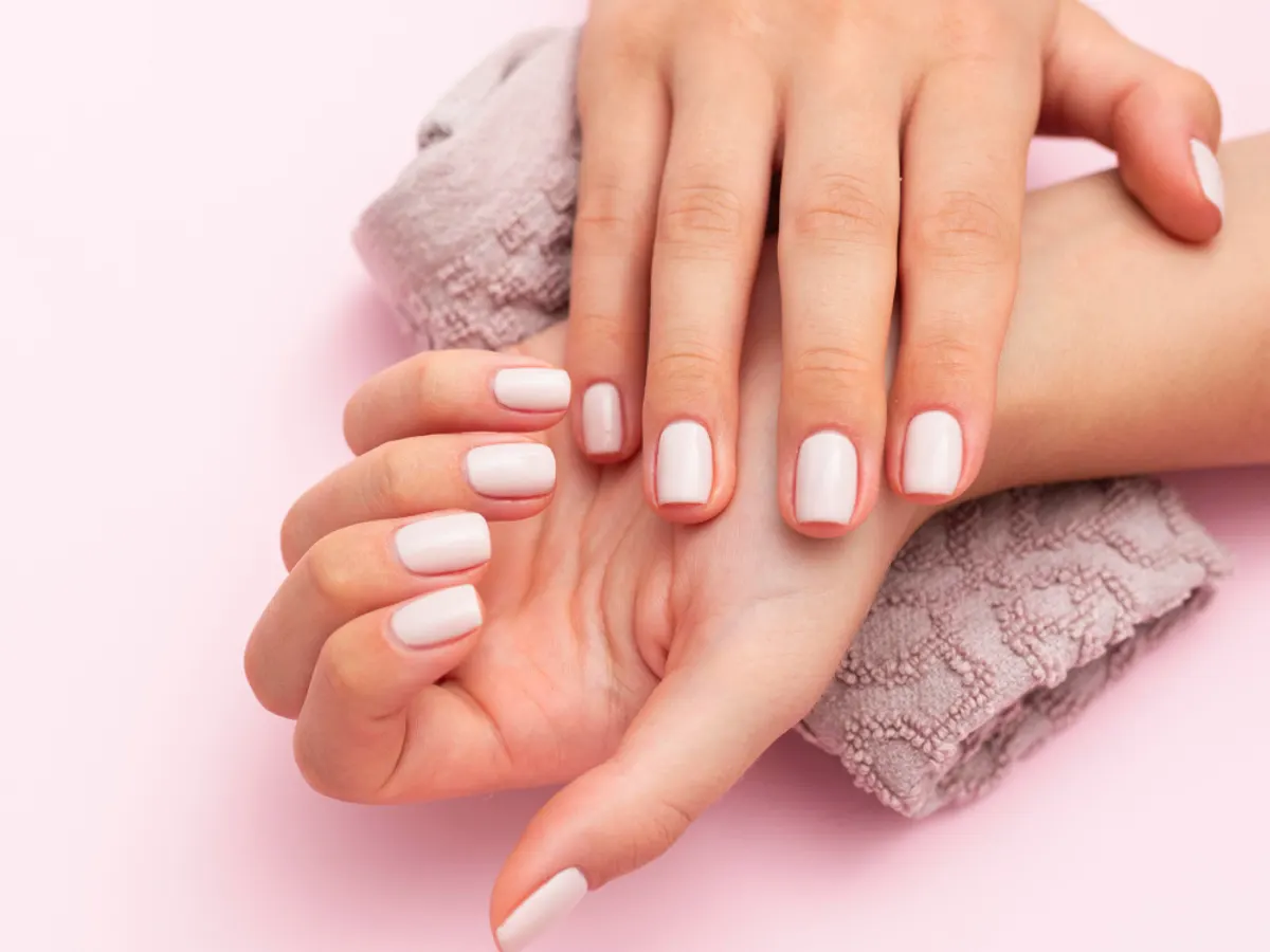 Mains aux ongles soignés et vernis posées sur une serviette